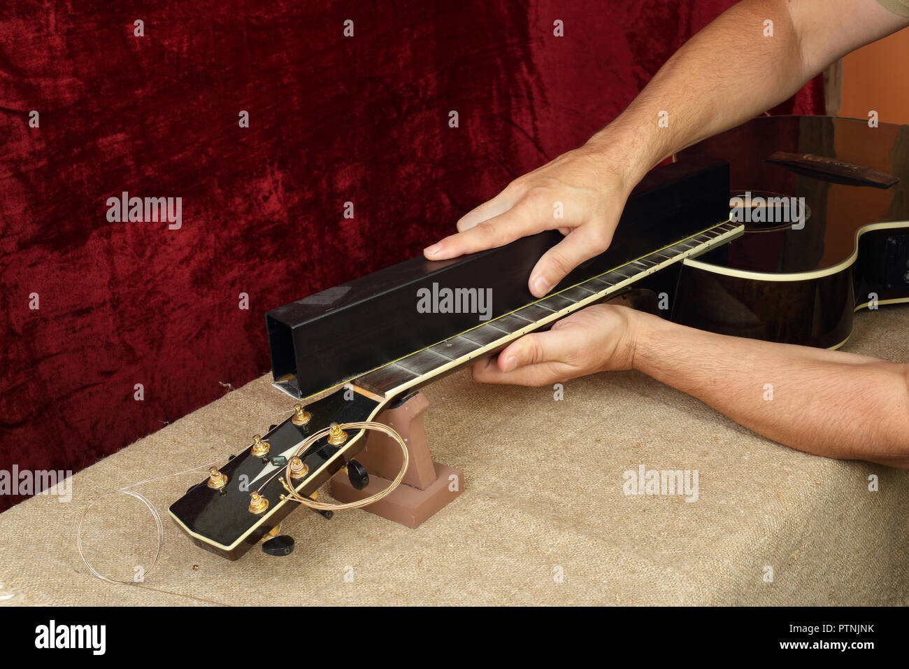Musical instrument guitar repair and service Worker grinds black acoustic guitar neck frets
