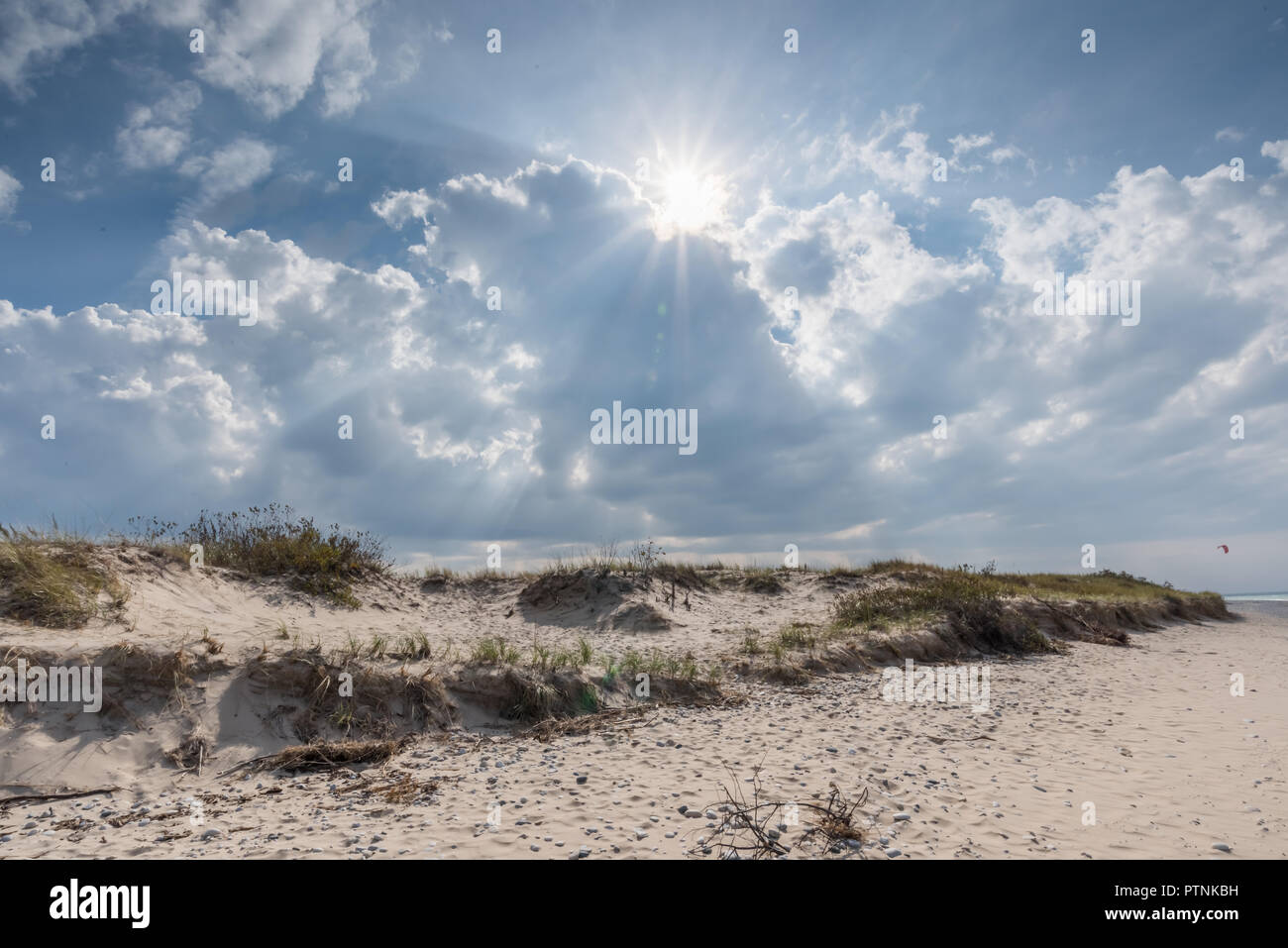 Sunburst coming out of the clouds over sand dunes. Stock Photo