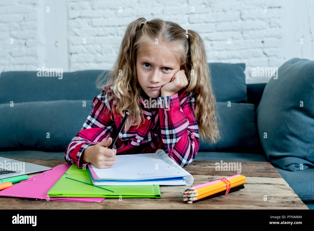 Beautiful cute blonde 9 years elementary student feeling sad bored and a overwhelmed trying to study at home in learning difficulties exams homework a Stock Photo