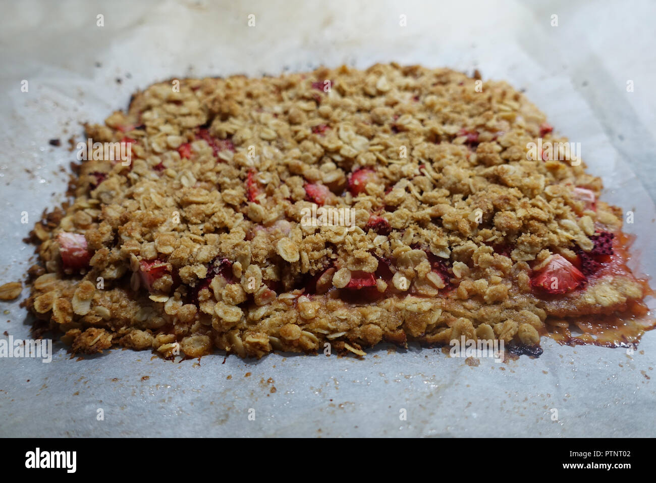 Baking oatmeal and strawberry pieces on a baking tray Stock Photo