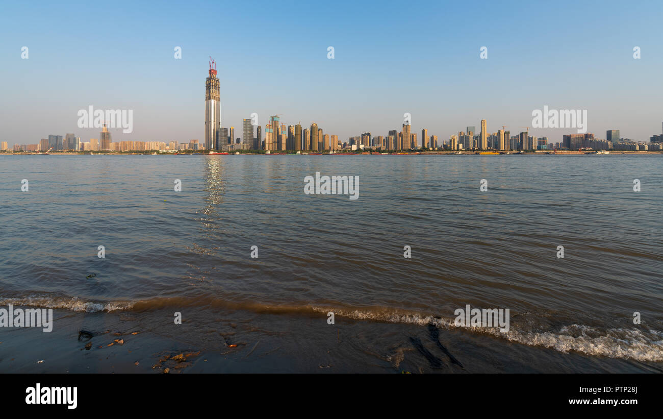Yangtze river bank with little wave and sand and Wuhan Wuchang district skyline in background in Wuhan Hubei China Stock Photo