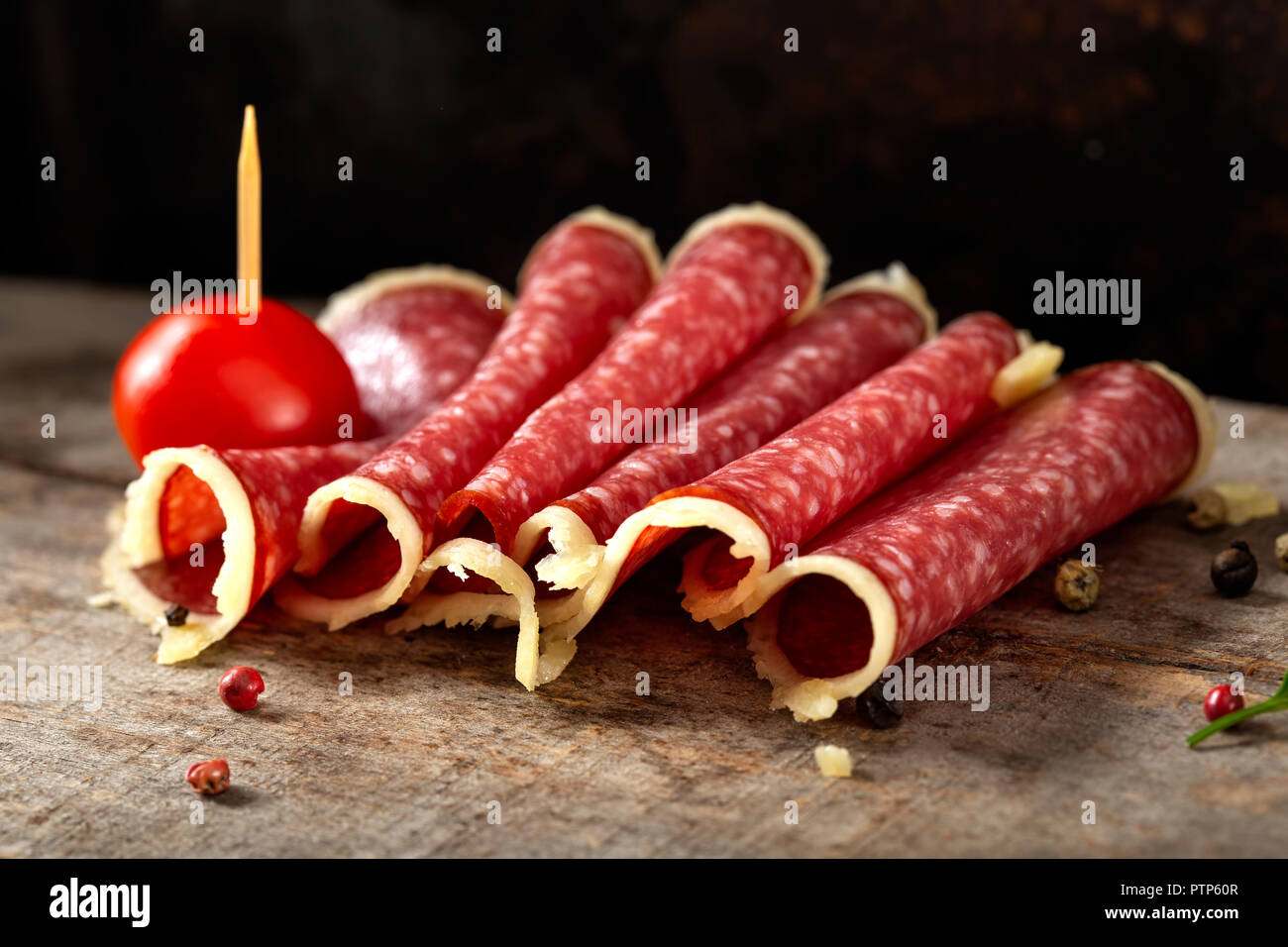 Slices of salami surrounded by parmesan cheese with peppercorns and cherry tomato Stock Photo