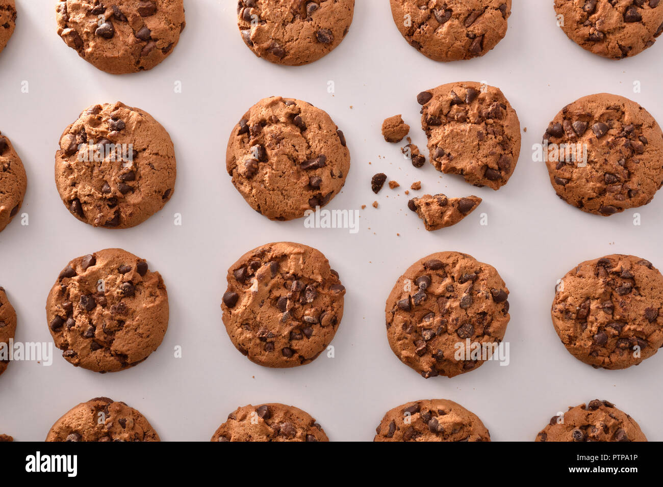 Breakfast with round biscuits pattern with black chocolate chips on white table in kitchen. Top view. Horizontal composition Stock Photo