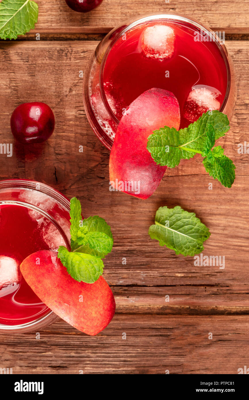 Overhead photo of vibrant red drinks with cherries on a rustic background with copyspace Stock Photo