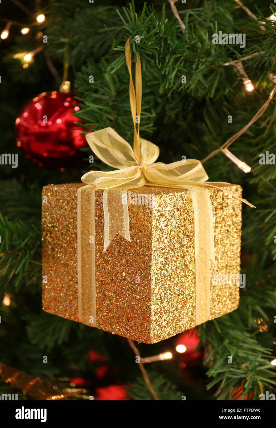 Vertical Photo of Gold Glitter Square Gift Box with Shiny Ribbon Bow Ornament for Christmas Decoration Stock Photo