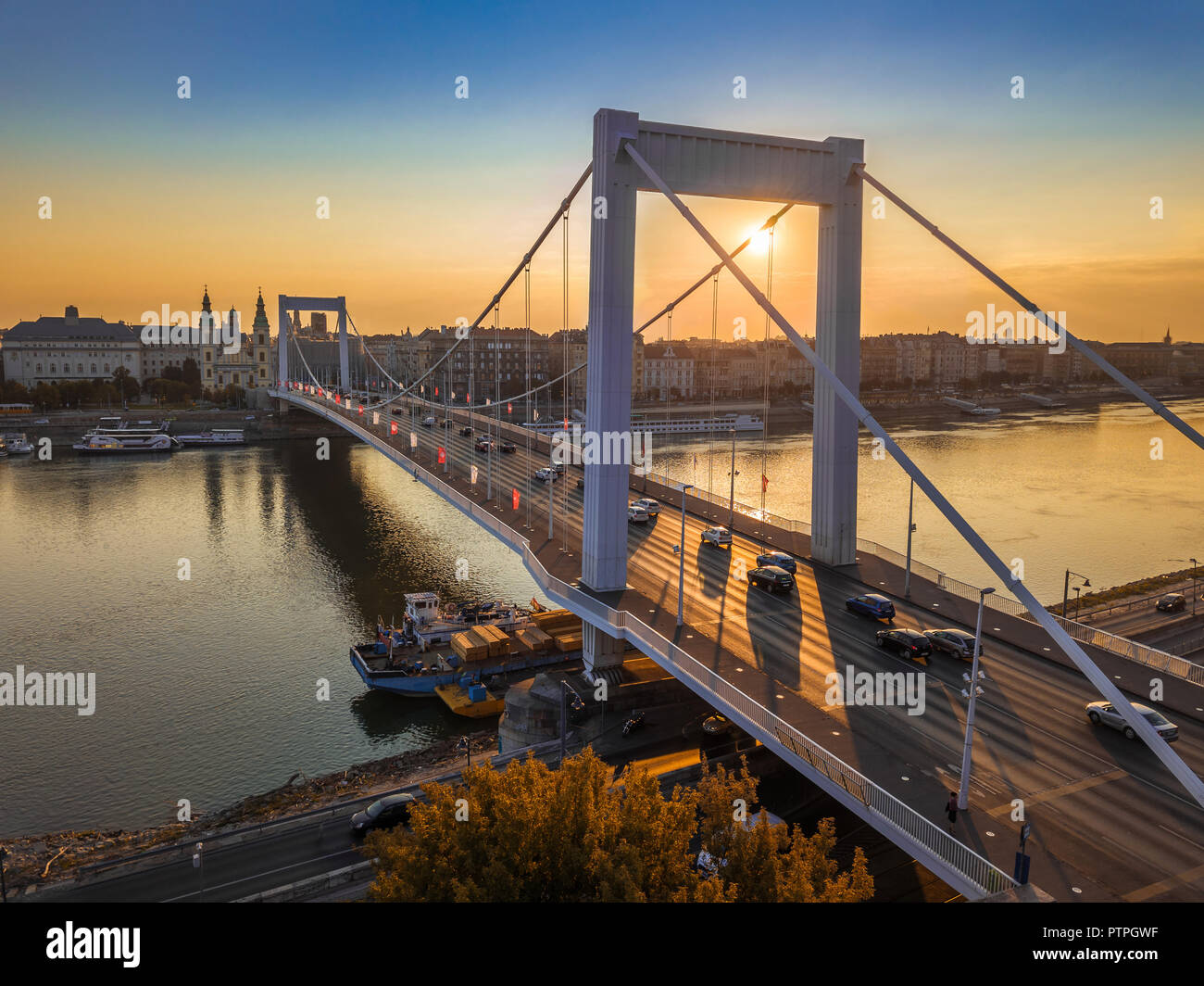 Budapest, Hungary - Beautiful Elisabeth Bridge (Erzsebet hid) at sunrise with golden and blue sky, heavy morning traffic and traditional yellow tram a Stock Photo