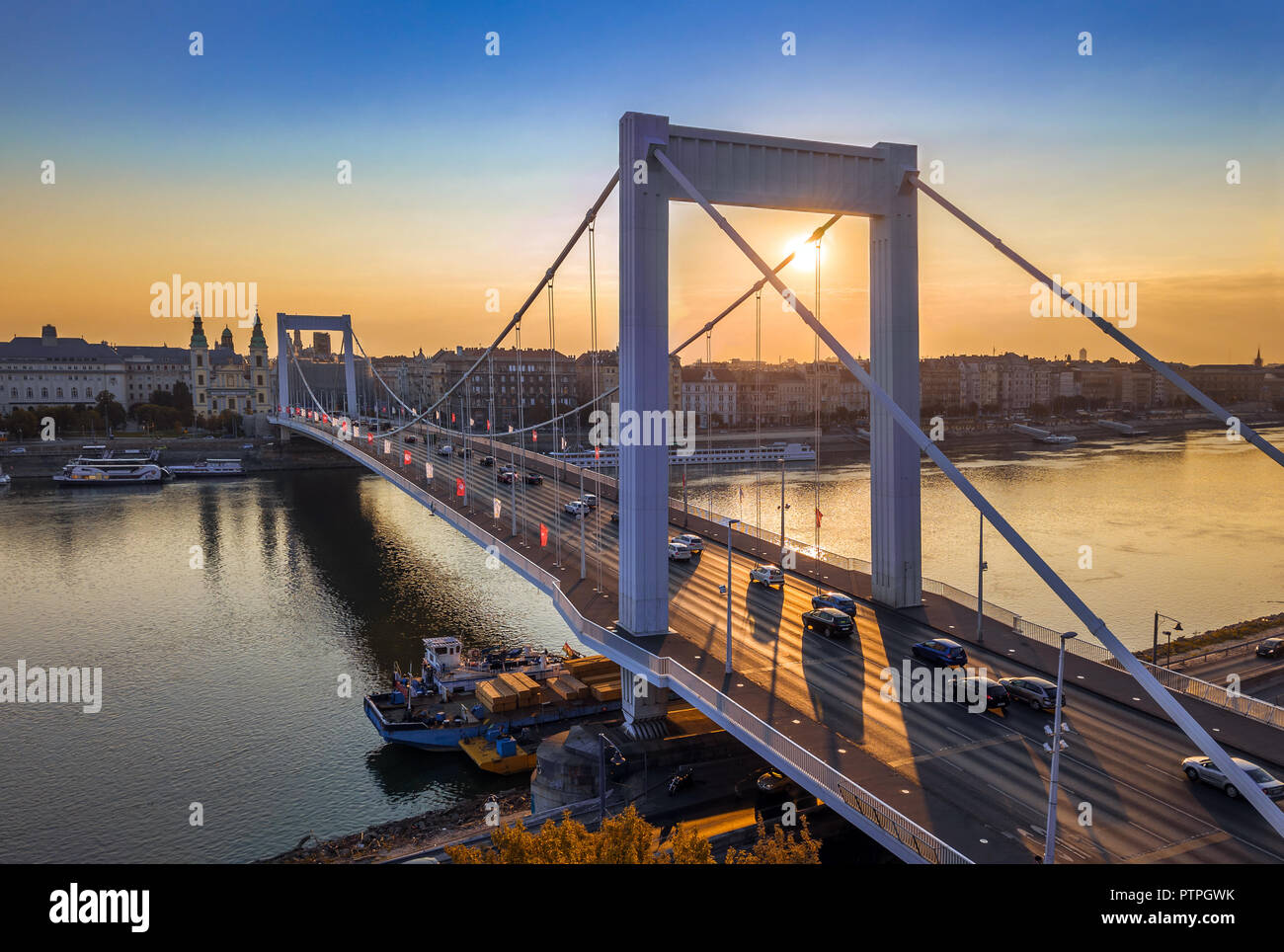 Budapest, Hungary - Beautiful Elisabeth Bridge (Erzsebet hid) at sunrise with golden and blue sky, heavy morning traffic and traditional yellow tram a Stock Photo