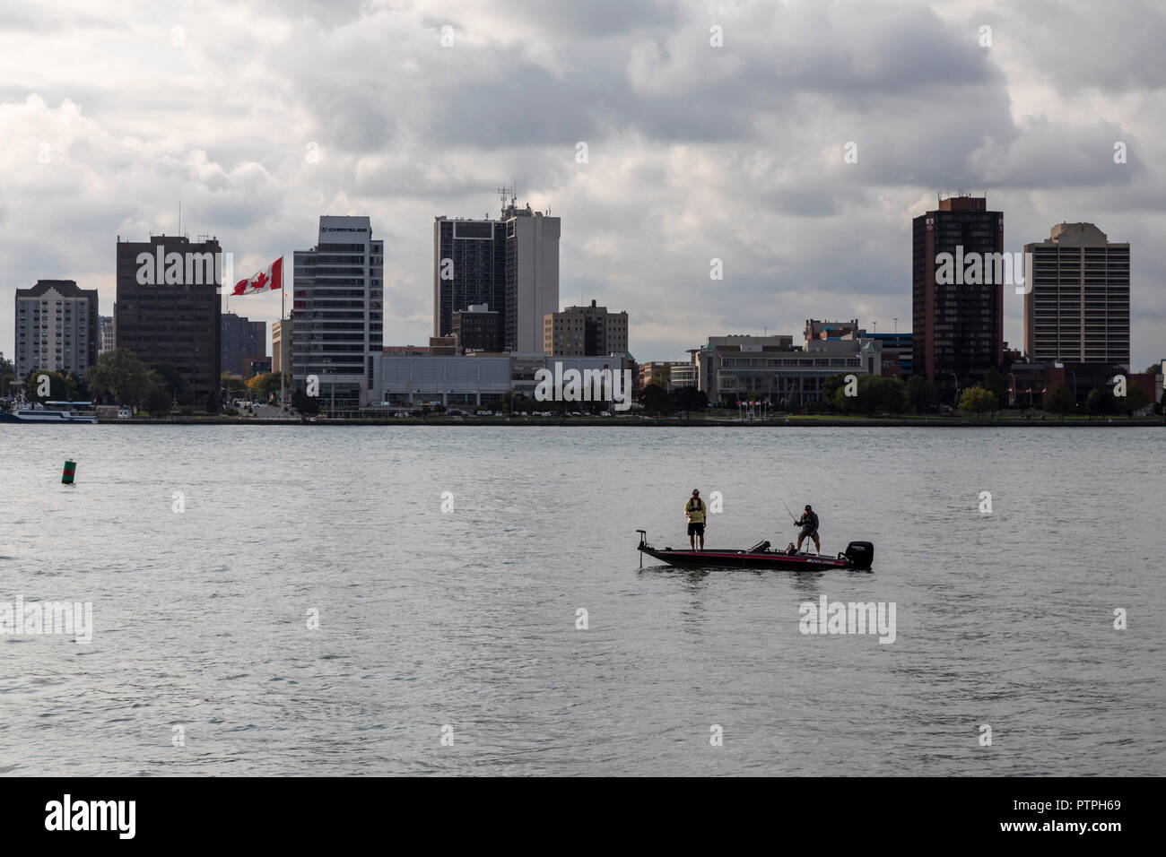 Detroit, Michigan - Two men fishing from a small boat on the Detroit River. Windsor, Ontario, Canada is on the far side. Stock Photo