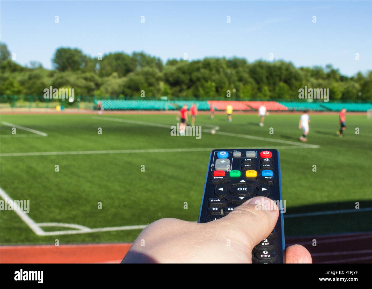 a male hand with a remote control from a TV set against the background of  the football field on which they play football Stock Photo - Alamy