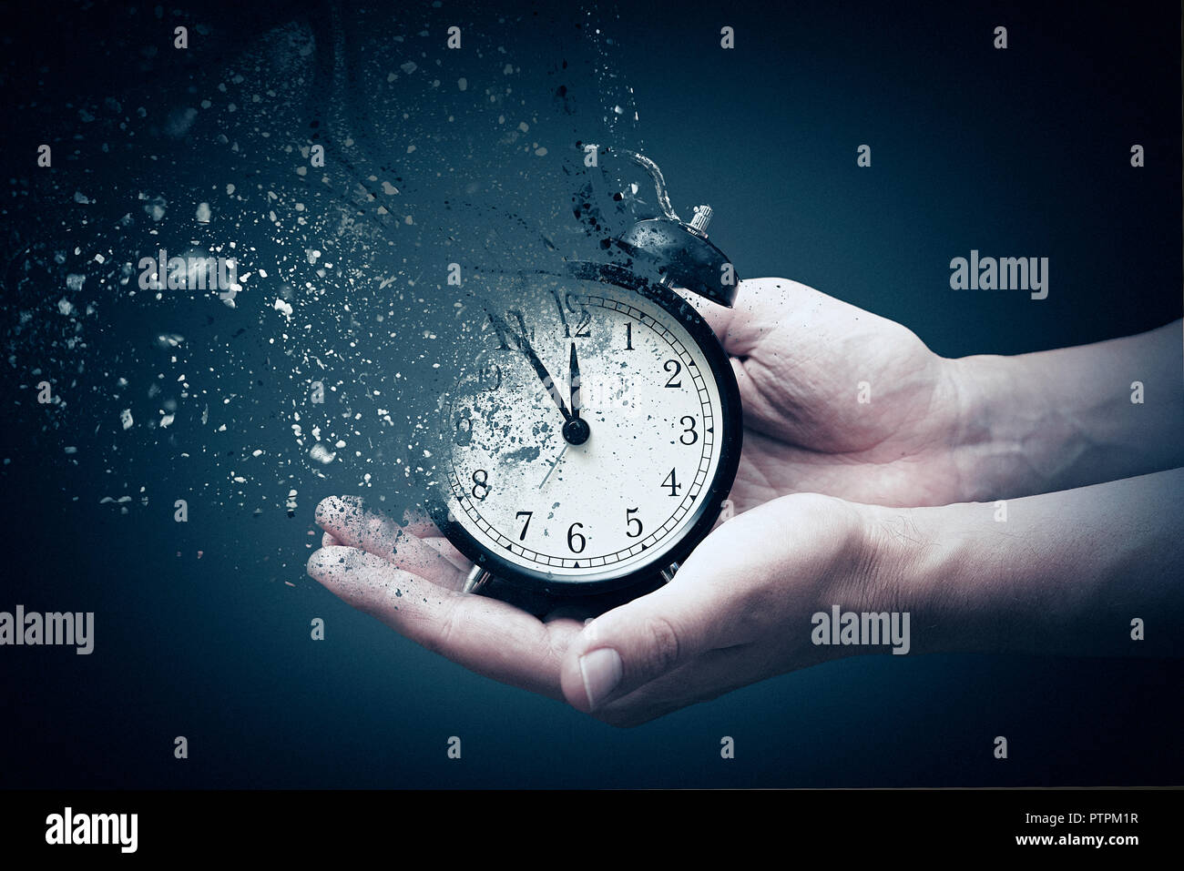 Concept of passing away, the clock breaks down into pieces. Hand holding analog clock with dispersion effect Stock Photo