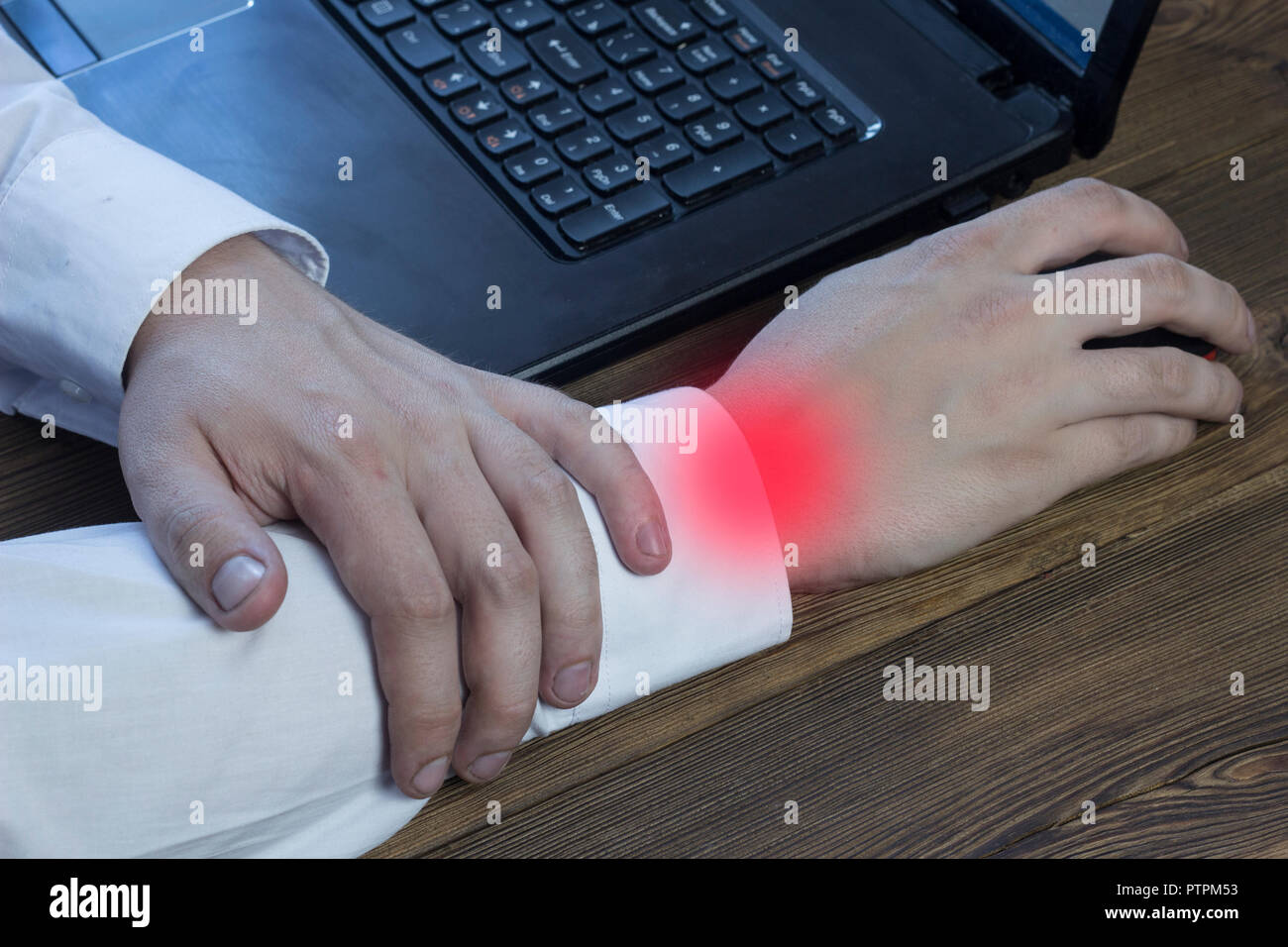 A man works at a computer and holds his hand, his arm hurts, tunnel