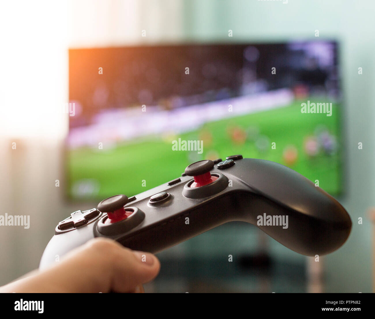 Men's hands with a joystick on the background of a TV, playing football,  close-up Stock Photo - Alamy