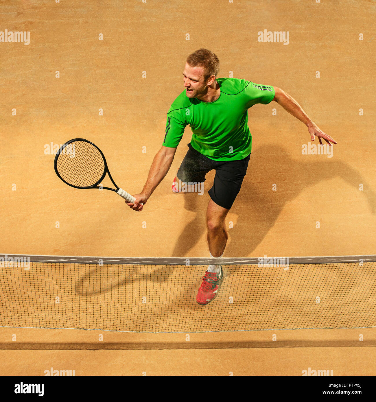 I am saving this ball now. Player lunge, game of defense. The one caucasian  fit man playing tennis at the earthen court . Player jumping in full length  with racquet and ball.