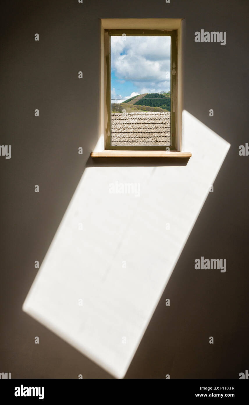 Room interior detail - painted white with small window and square of sunlight on wall Stock Photo