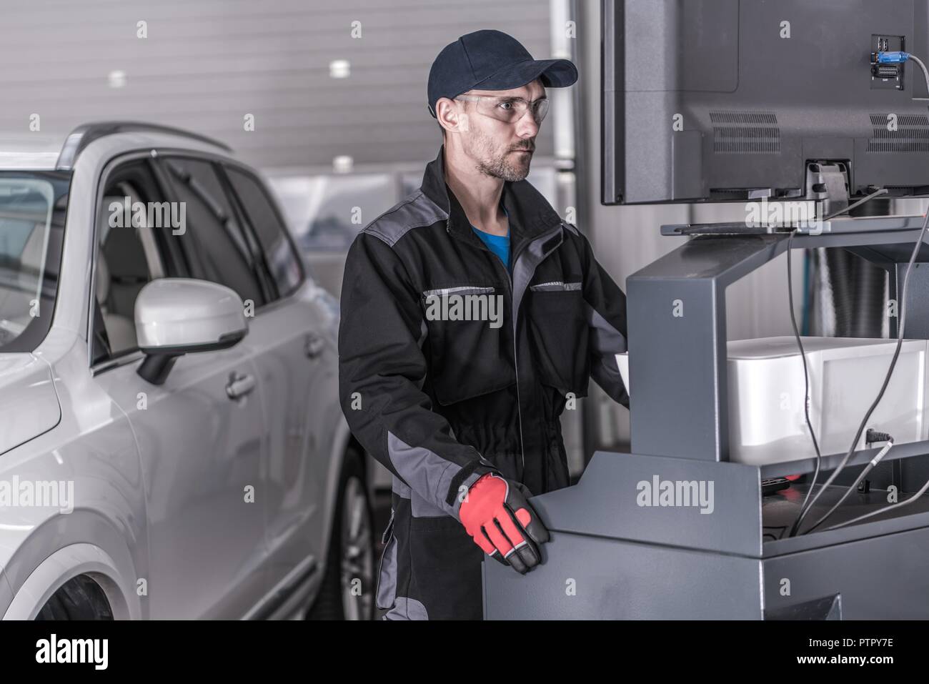 Auto Service Technician in Front of the Computer Analyzing Data From the Vehicle. Stock Photo