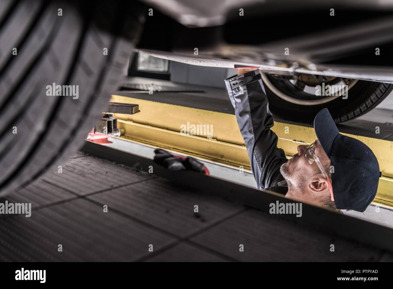 Mechanic Servicing Car. Checking Undercarriage Elements. Vehicle Maintenance. Stock Photo