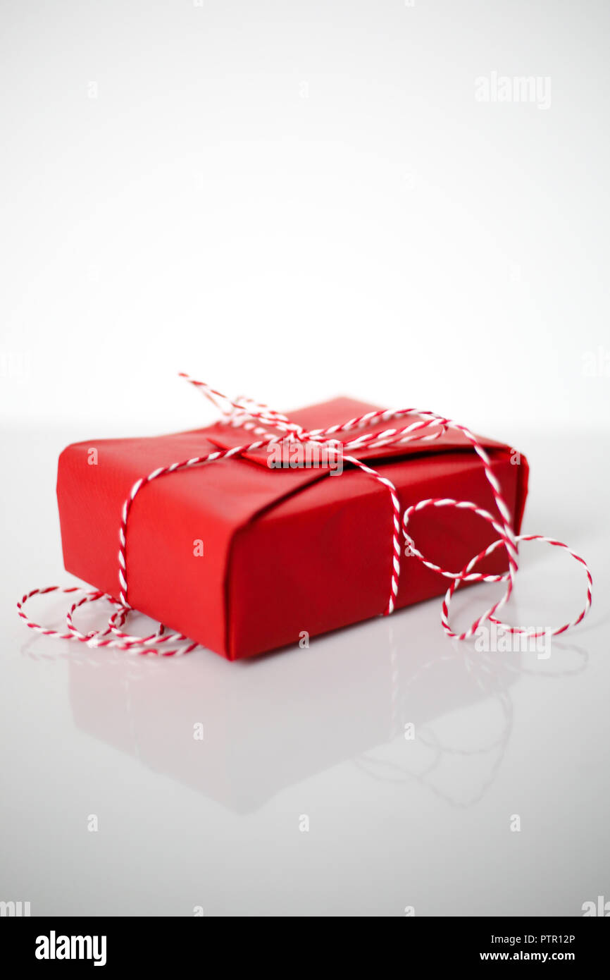 Christmas gift box wrapped in red paper and bow of dtriped rope on ...