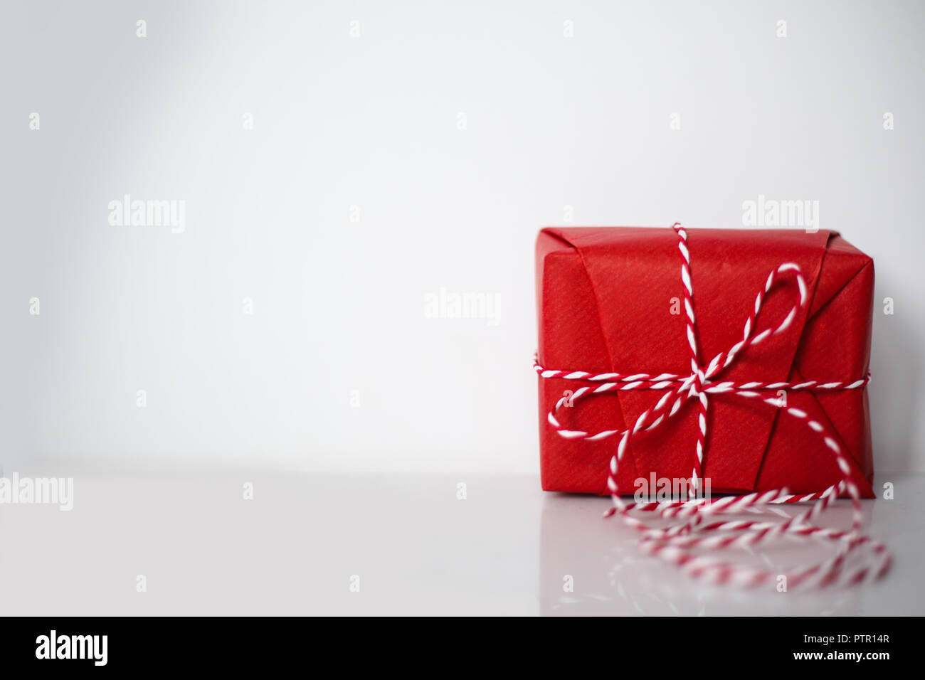 Christmas gift box wrapped in red paper and bow of dtriped rope on ...