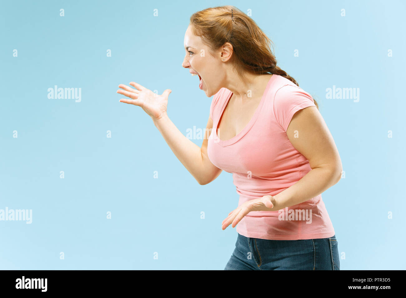 Argue, arguing concept. Beautiful female half-length portrait isolated on blue studio backgroud. Young emotional surprised woman looking at camera.Human emotions, facial expression concept. Stock Photo