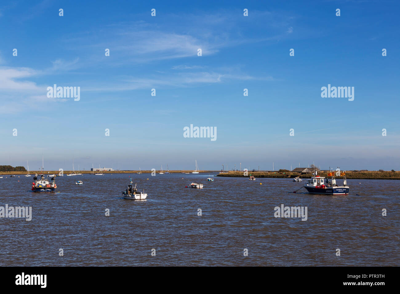 Boats Anchored and Moored on the River Ore Seperating Orford from Orford Ness on a Very Sunny October Afternoon Stock Photo