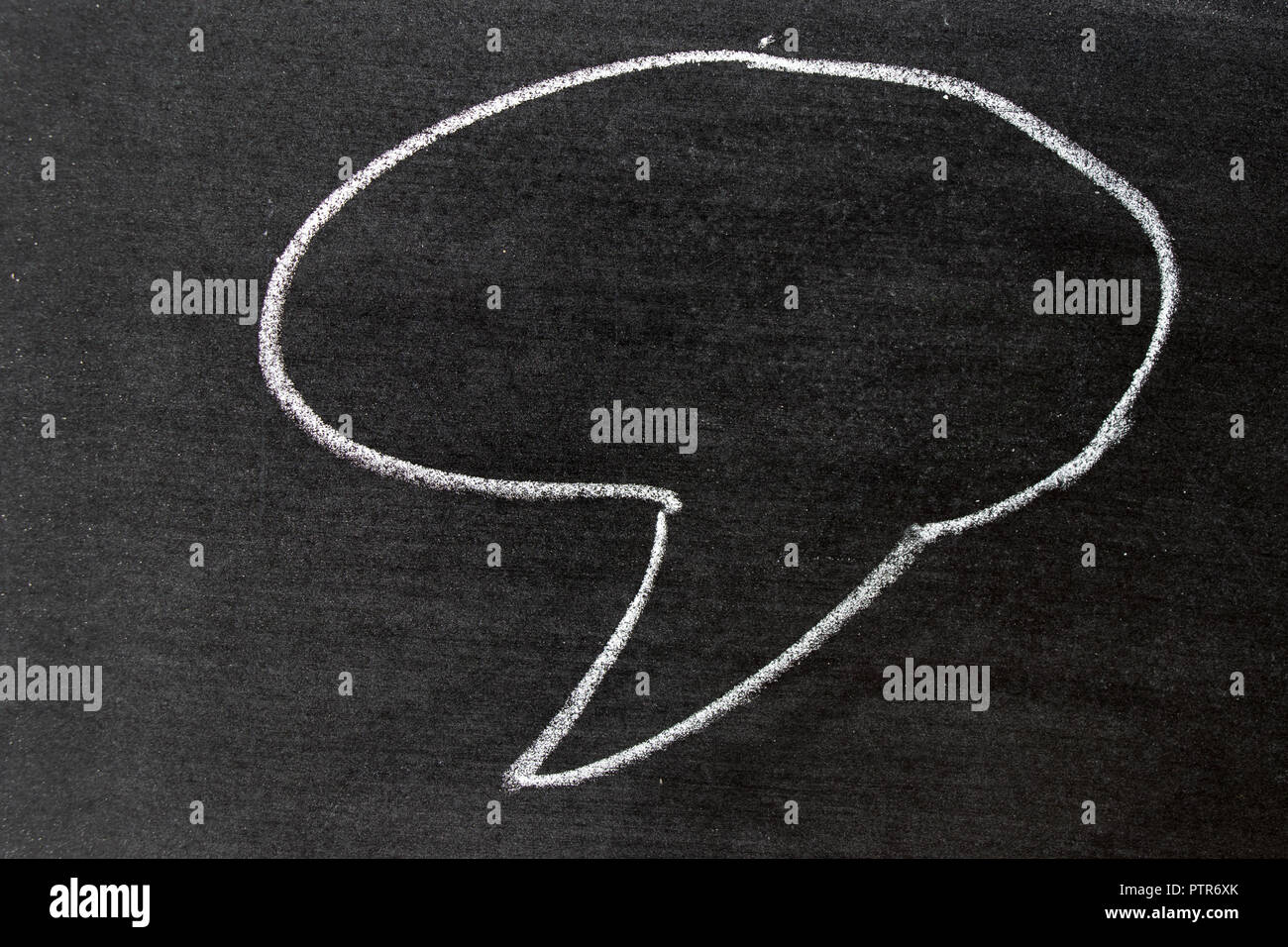 White color chalk hand drawing as speech bubble shape on black board ...