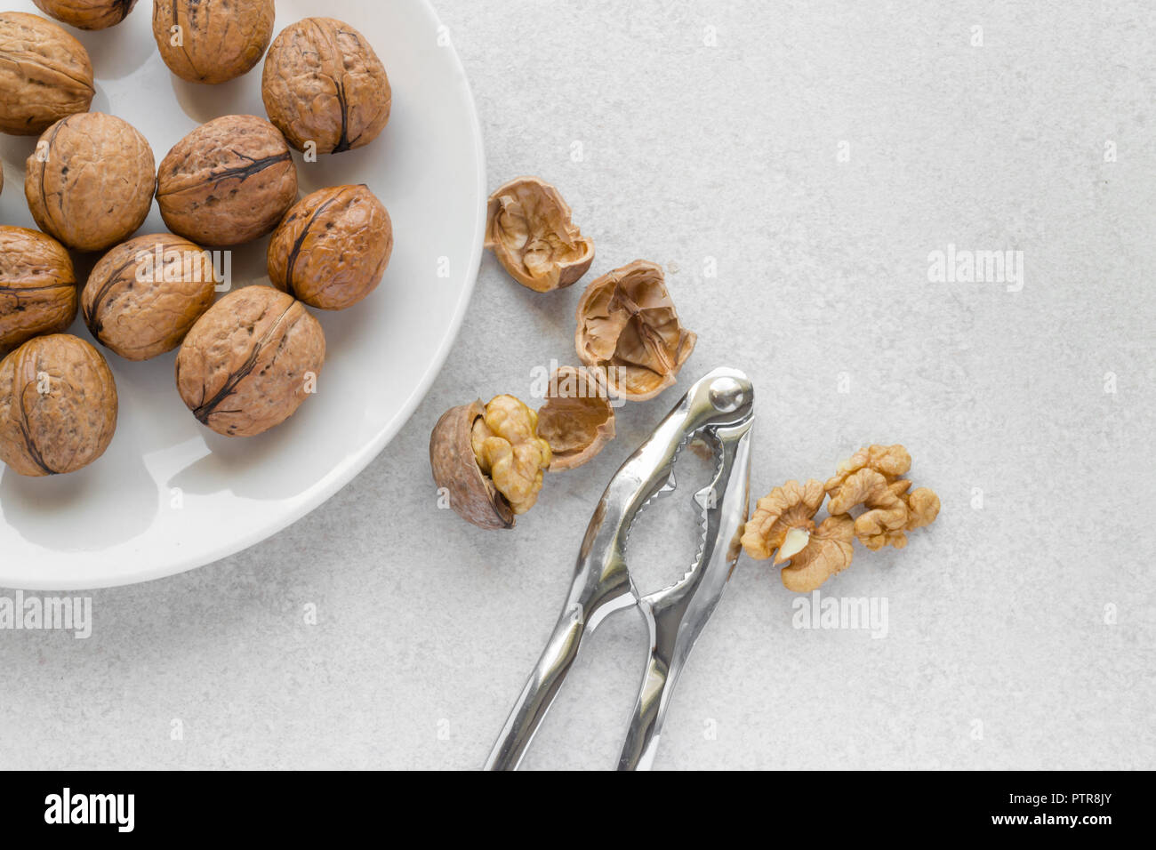 Walnuts on a plate, metal nutcracker on white background Stock Photo