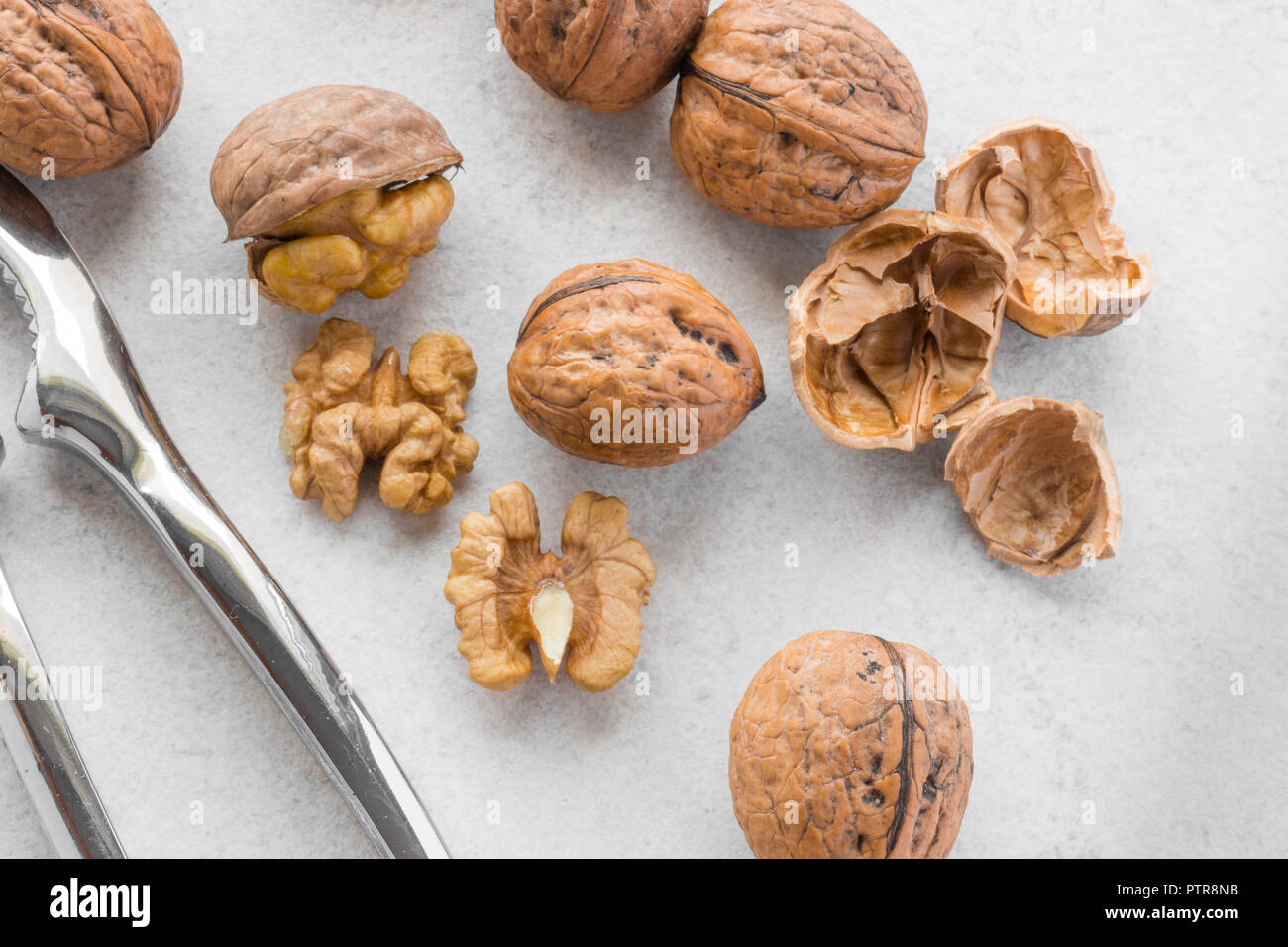 Some walnuts and silver nutcracker on grey background Stock Photo