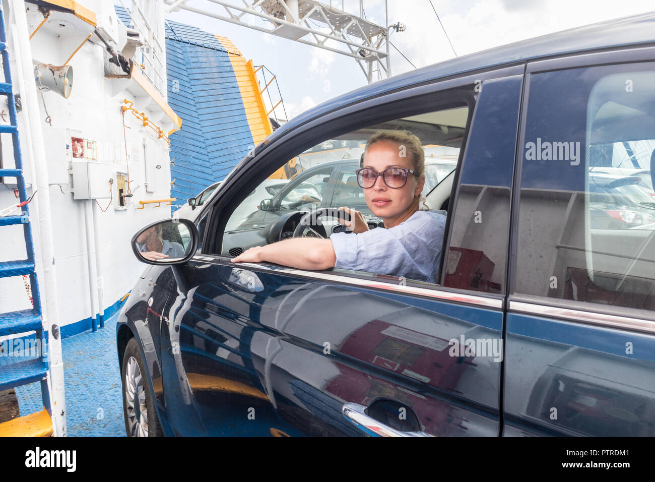 Female driver parking her car on ferry boat on trip to their summer