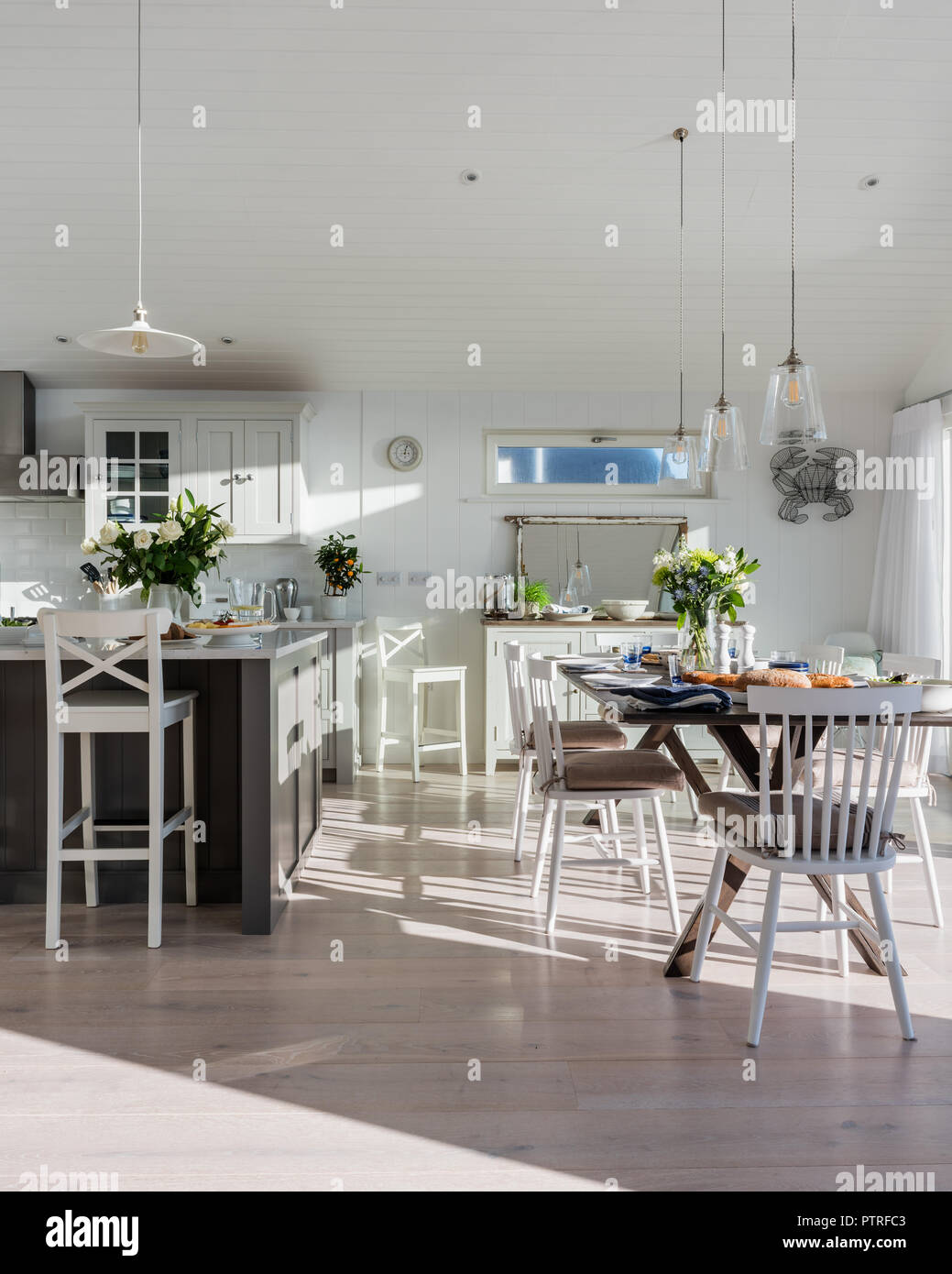 Open plan dining room in sunlit coastal home Stock Photo