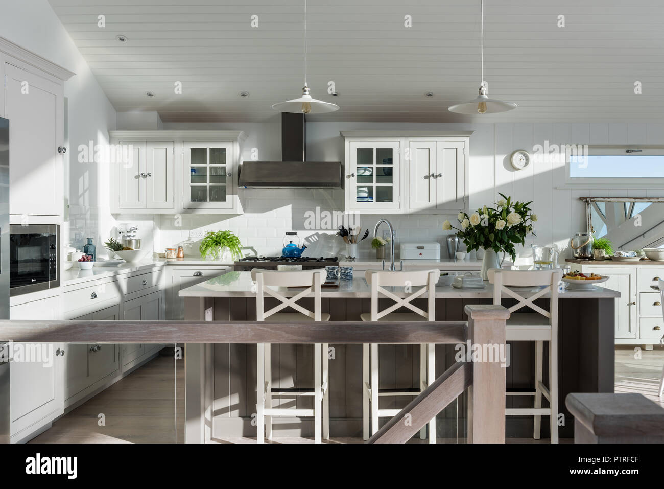 Shaker-style kitchen with pendant lights and white roses Stock Photo