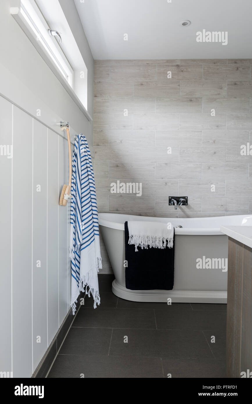 Striped towel and backbrush beside freestanding bath in coastal home Stock Photo