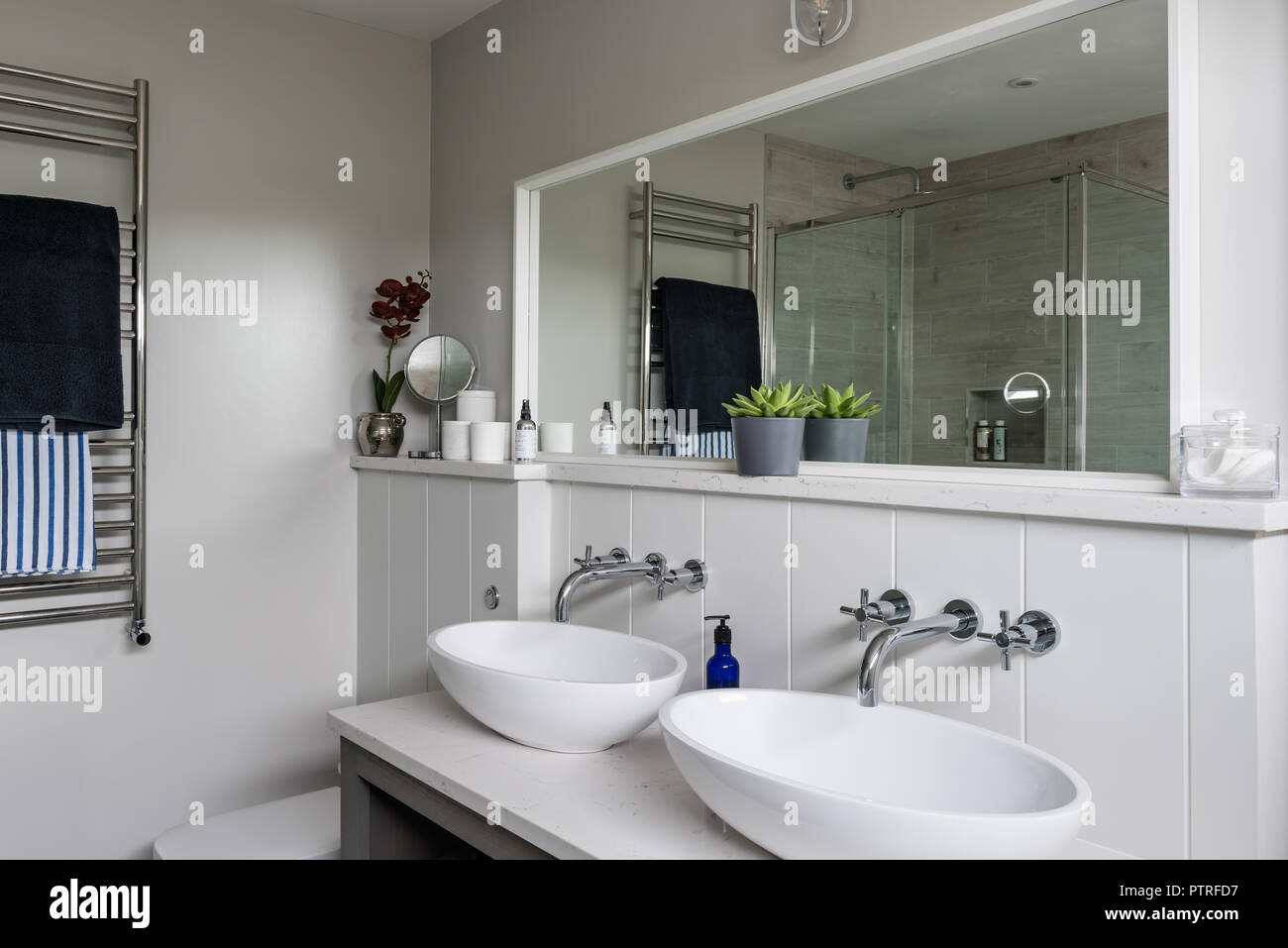 Large mirror reflects light above double basins in coastal home Stock ...