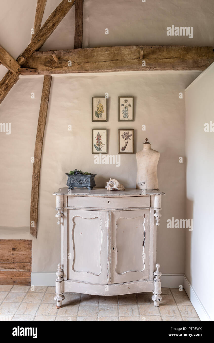 16th century farmhouse renovation Mannequin on sideboard with botanical prints in restored 16th century farmhouse Stock Photo