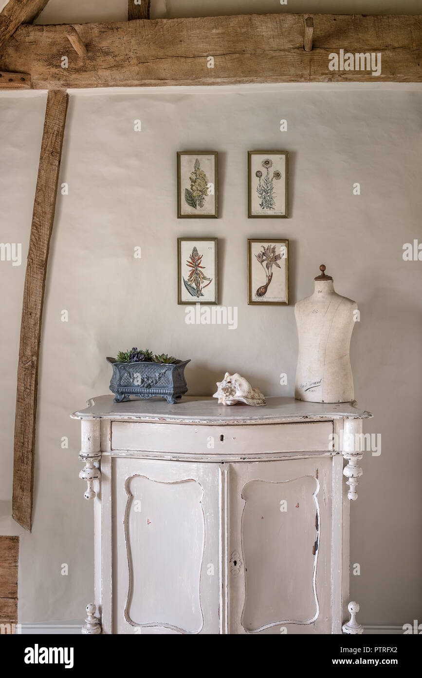 16th century farmhouse renovation Mannequin on sideboard with botanical prints in restored 16th century farmhouse Stock Photo