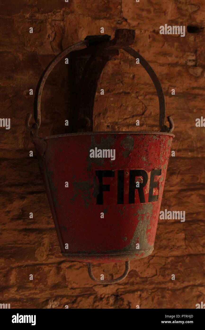Vintage / Retro - Red Fire Bucket hangs from a wall. Stock Photo