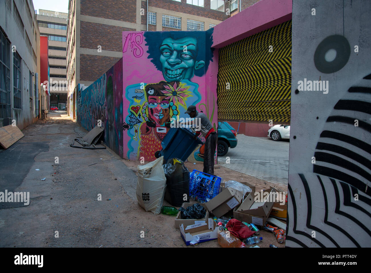 Johannesburg, South Africa, Wednesday, Oct. 10, 2018. A man takes out the trash as the annual "City Of Gold" Urban Art Festival kicked off its graffiti street tour in Johannesburg today.  Labelled vandalism by some, the festival highlights the positive aspects of this art form and seeks to increase the appreciation for it among the general public.   These mural projects often enhance and activate sites in the Johannesburg inner-city area that are either forgotten or feared by the city's inhabitants, organizers said. Credit: Eva-Lotta Jansson/Alamy Live News Stock Photo