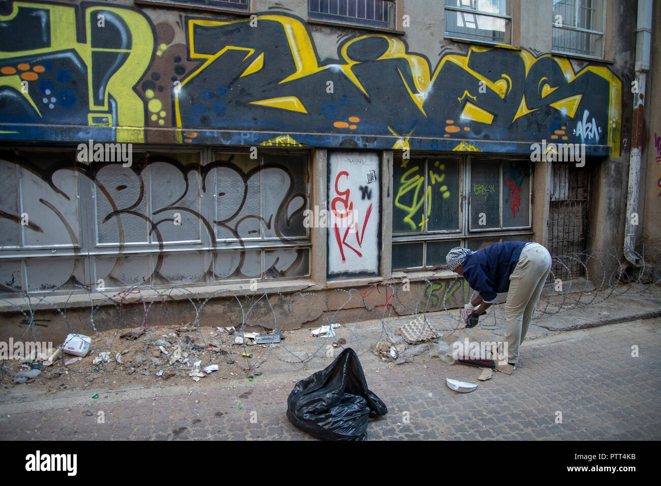 Johannesburg, South Africa, Wednesday, Oct. 10, 2018. A woman cleans in an alleyway as the annual "City Of Gold" Urban Art Festival kicked off its graffiti street tour in Johannesburg today. Labelled vandalism by some, the festival highlights the positive aspects of this art form and seeks to increase the appreciation for it among the general public. These mural projects often enhance and activate sites in the Johannesburg inner-city area that are either forgotten or feared by the city's inhabitants, organizers said. Credit: Eva-Lotta Jansson/Alamy Live News Stock Photo