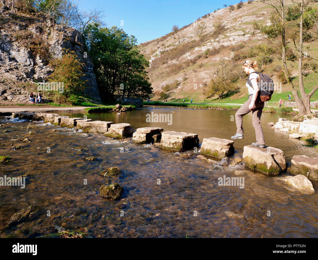 Peak District National Park, Derbyshire, UK. 10th October, 2018. UK Weather Woman crossing the stepping stones on an unusually hot sunny October day in the tourist hotspot of Dovedale in the Peak District National Park, Derbyshire Credit: Doug Blane/Alamy Live News Stock Photo