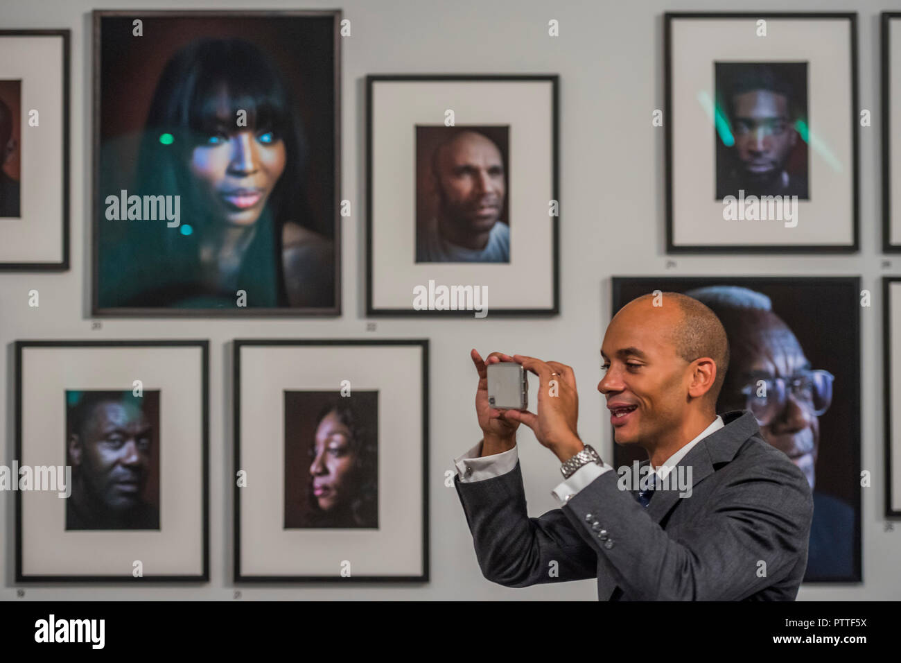 London, UK. 10th October, 2018. Chuka Umunna MP uses the app - Black is the New Black: Portraits by Simon Frederick at National Portrait Gallery, London, the Gallery’s largest acquisition of portraits of Afro-Caribbean (on display until 27 January 2019). Credit: Guy Bell/Alamy Live News Stock Photo