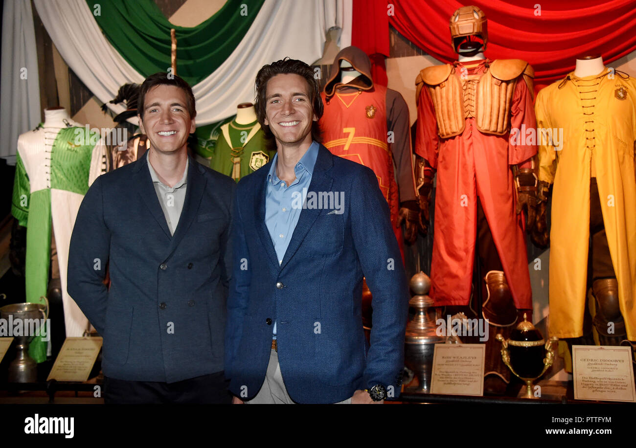 Potsdam, Brandenburg. 11th Oct, 2018. The actors James (r) and Oliver Phelps who are the Weasley twins in the Harry Potter films stand in front of Quidditch costumes at the press conference for the 'Harry Potter' exhibition. The exhibition, which opens for visitors on Saturday (13.04.2018) in the Filmpark Babelsberg, shows costumes and complete sets of the film series. Credit: Bernd Settnik/dpa-Zentralbild/dpa/Alamy Live News Stock Photo