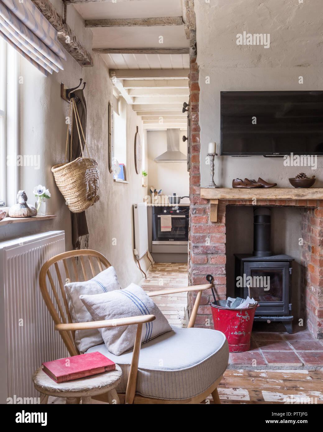 Stripped Ercol-style armchair and woodburner in exposed brick fireplace Stock Photo