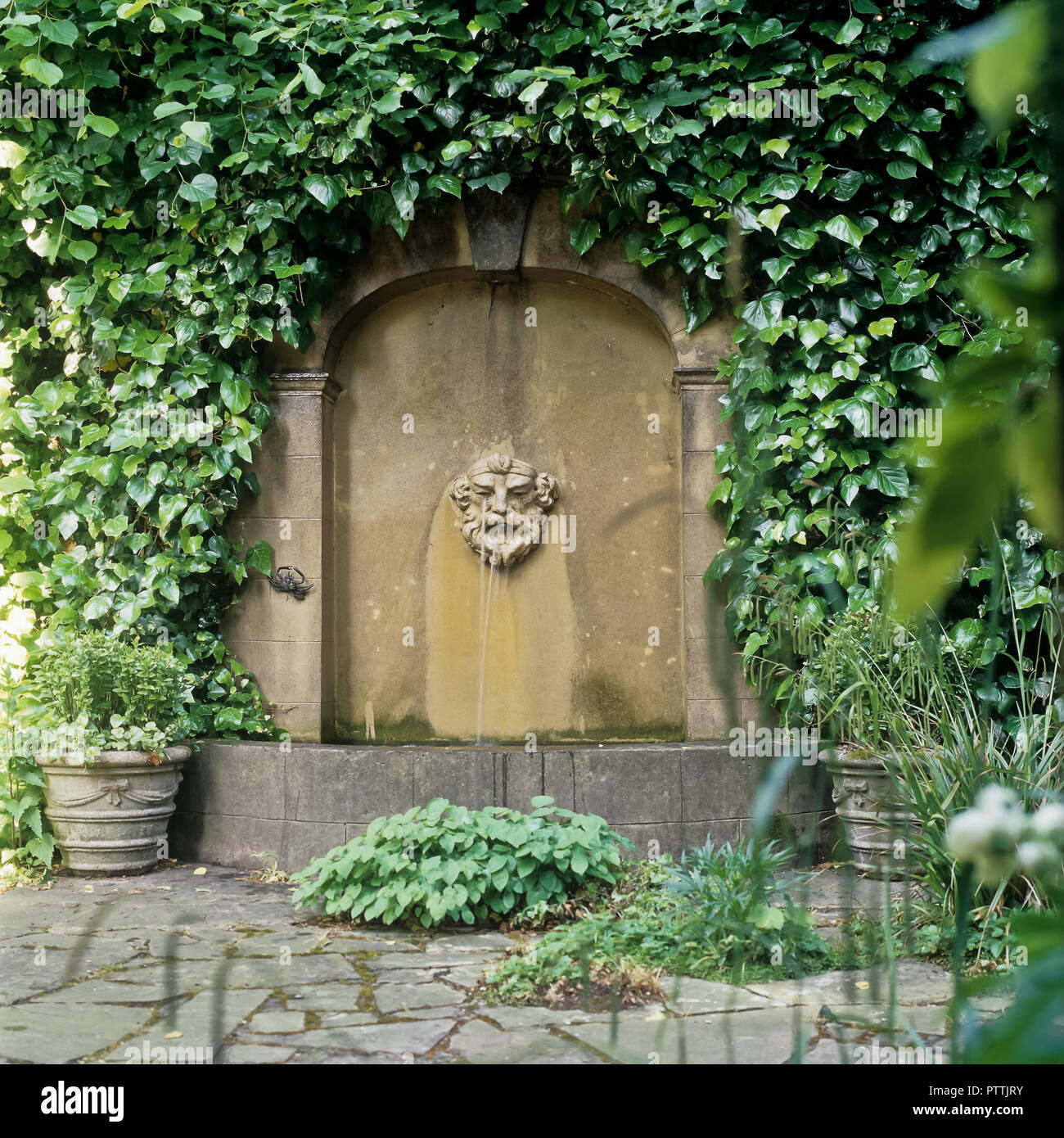 Water spout on arched stone wall in Kensington Garden Stock Photo