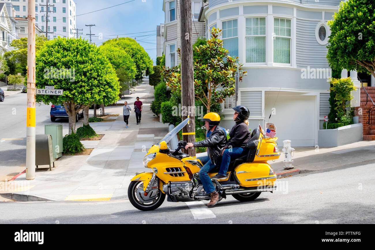 A beautiful yellow motorcycle pauses in Pacific Heights in San Francisco outside the house where Mrs Doubtfire was filmed Stock Photo