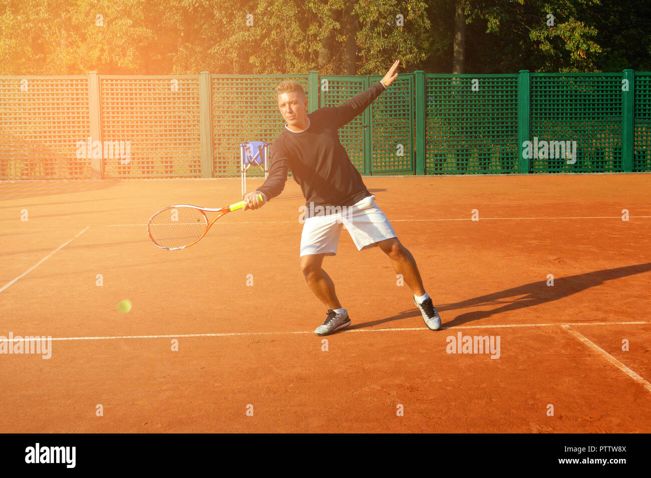 Tennis match which a serving player with sunlight in background Stock