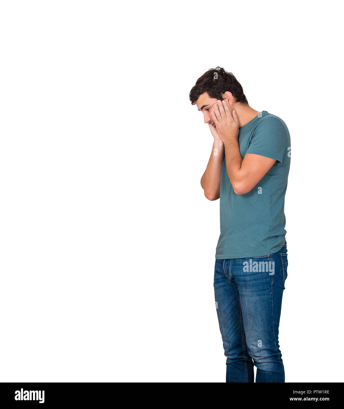 Side view of a disappointed and stressed young man hands on cheeks looking down isolated over white background with copy space. Sad feeling, negative  Stock Photo