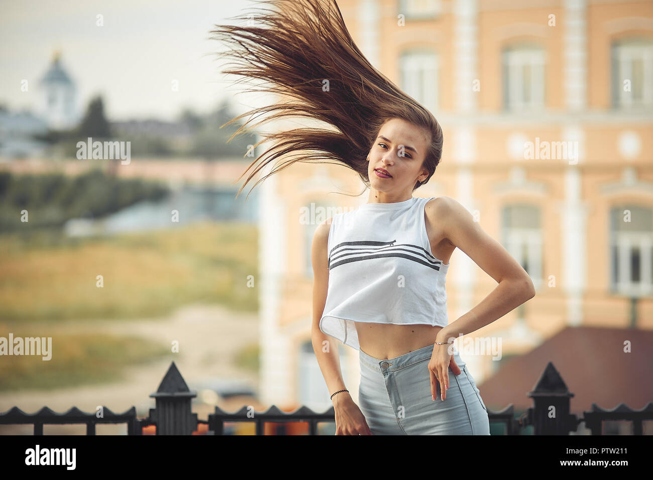 portrait of a girl in jeans and a t-shirt on the background of the building in the evening on a summer day. street dancing in the city Stock Photo