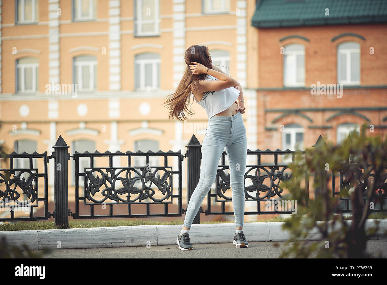 portrait of a girl in jeans and a t-shirt on the background of the building in the evening on a summer day. street dancing in the city Stock Photo