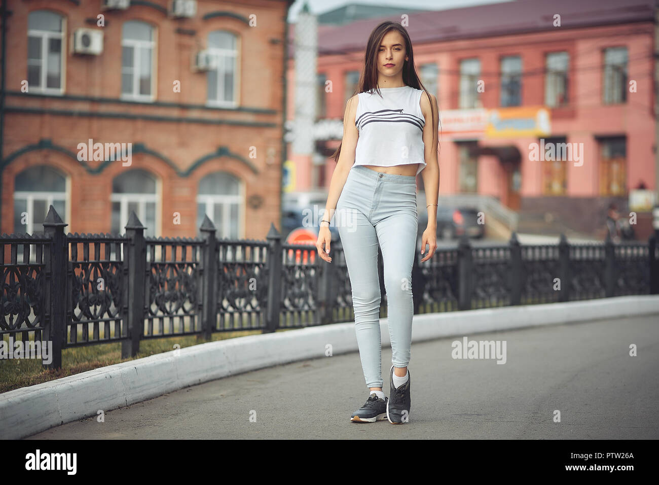 portrait of a girl in jeans and a t-shirt on the background of the building in the evening on a summer day. street dancing in the city Stock Photo