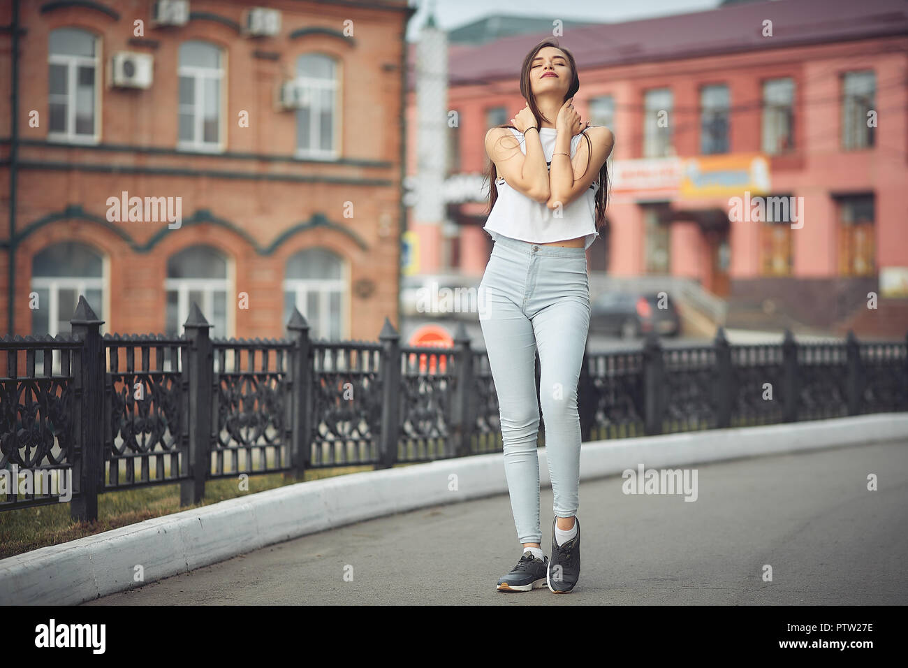 portrait of a girl in jeans and a t-shirt on the background of the building in the evening on a summer day. street dancing in the city Stock Photo