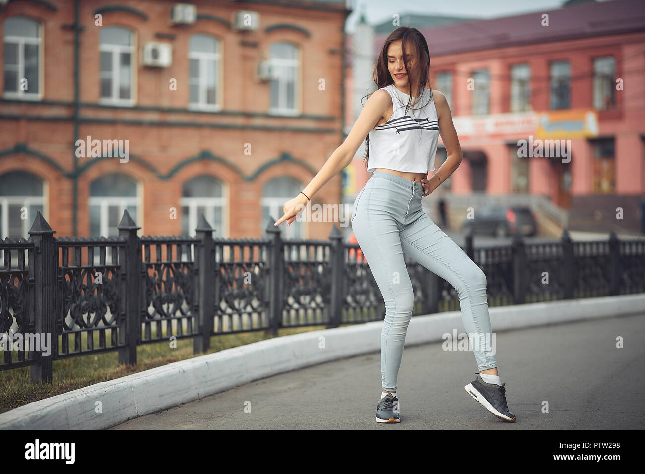 portrait of a girl in jeans and a t-shirt on the background of the building in the evening on a summer day. street dancing in the city Stock Photo